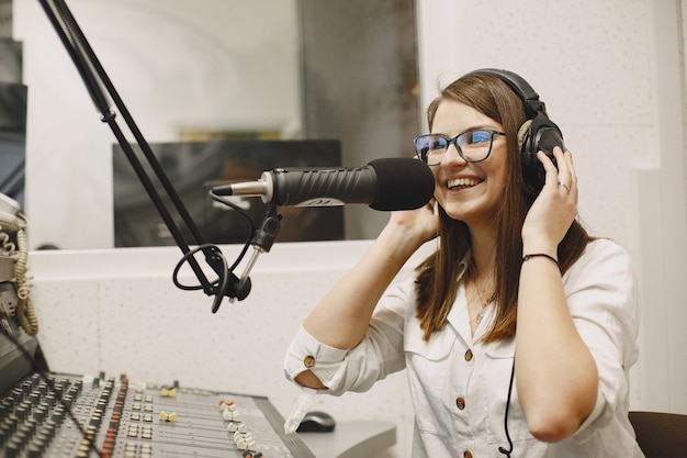 Vrouwelijke gastheer die op microfoon communiceert. Vrouw in radiostudio.