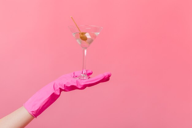 Vrouwelijke gehandschoende hand met glas martini met olijf
