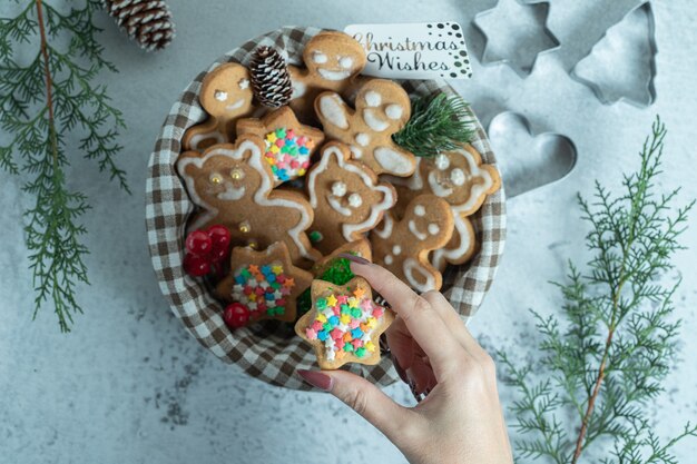 Vrouwelijke hand die kerstkoekje uit de mand haalt.