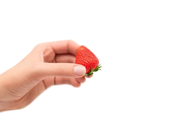 Vrouwelijke hand die rijpe rode aardbei houdt die op witte achtergrond wordt geïsoleerd.