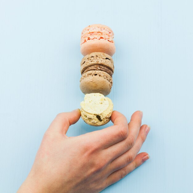 Vrouwelijke hand die smakelijke makarons neemt