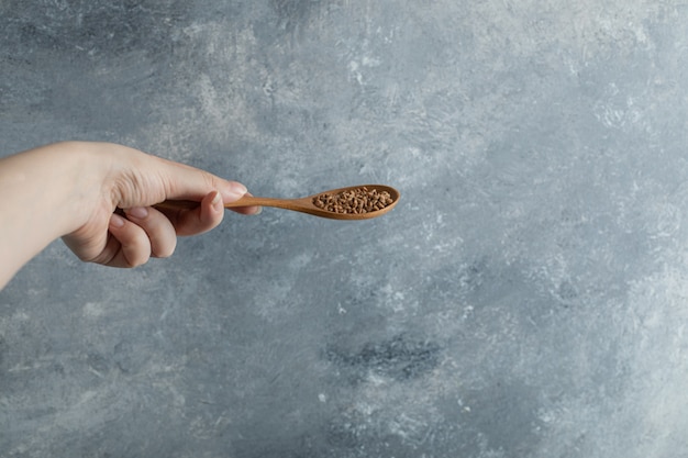 Vrouwelijke hand met houten lepel rauwe boekweit