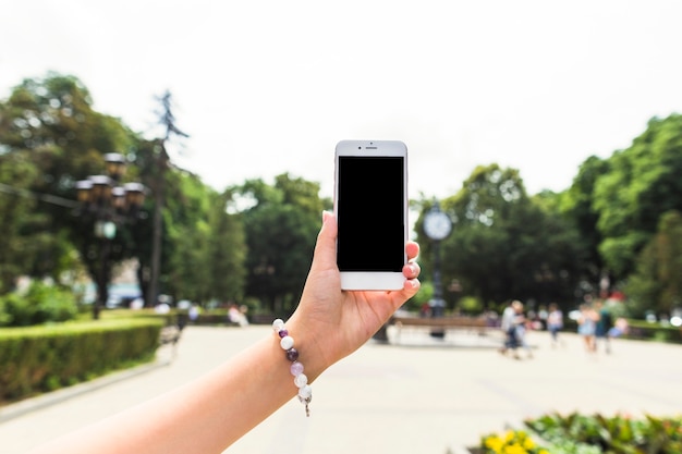 Vrouwelijke hand met mobiele telefoon in de open lucht