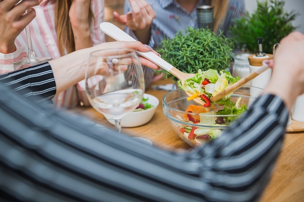 Gratis foto vrouwelijke handen die salade met houten lepels nemen