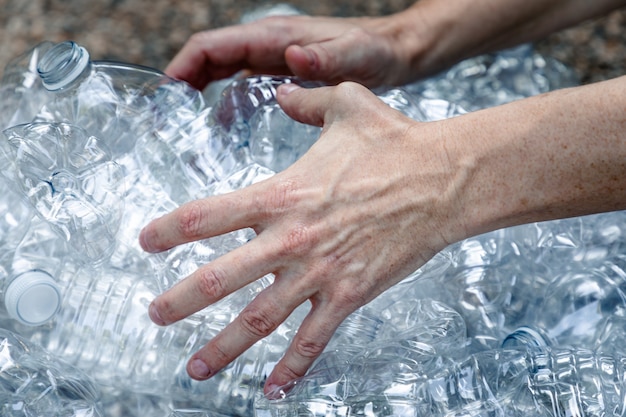 Vrouwelijke handen grijpen plastic flessen om ze te verzamelen en weg te gooien