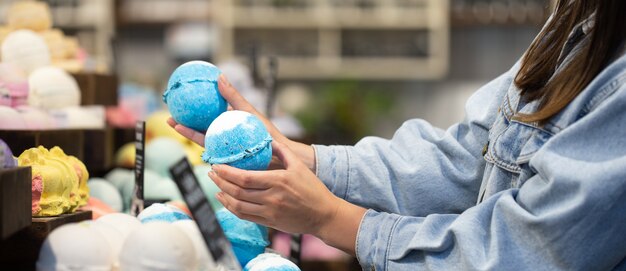 Vrouwelijke handen houden heldere badbommen in een cosmetica-winkel. Lichaamsverzorging concept.