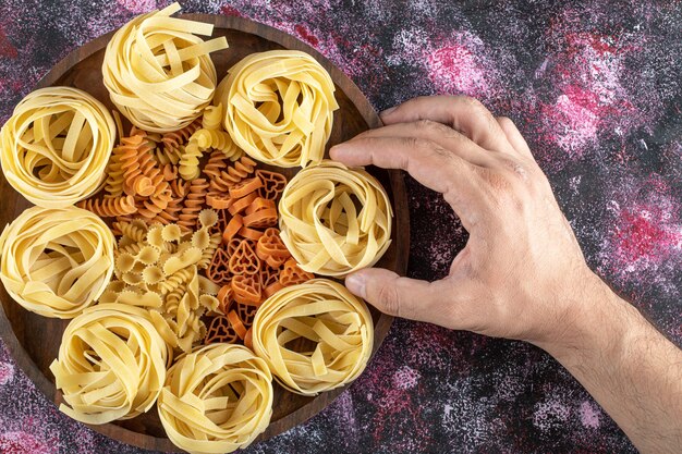 Vrouwelijke handen met pasta nest van plaat.