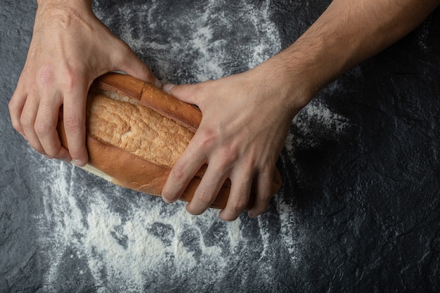 Vrouwelijke handen met vers gebakken brood, close-up.