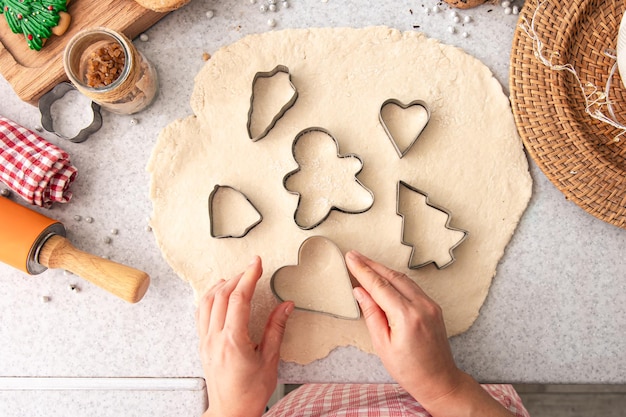 Vrouwelijke handen snijden vormen en maken kerstkoekjes