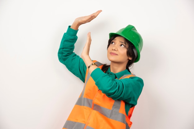 Vrouwelijke industrieel ingenieur in uniform met helm op witte achtergrond.