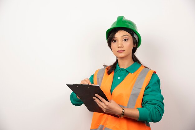 Vrouwelijke industrieel ingenieur in uniform met klembord op witte achtergrond.