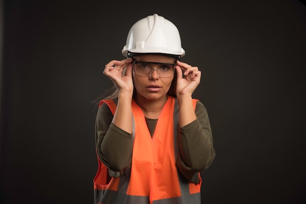 Vrouwelijke ingenieur die een witte helm, een bril en een uitrusting draagt.