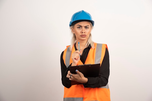 Vrouwelijke ingenieur die intens op witte achtergrond kijkt. Hoge kwaliteit foto