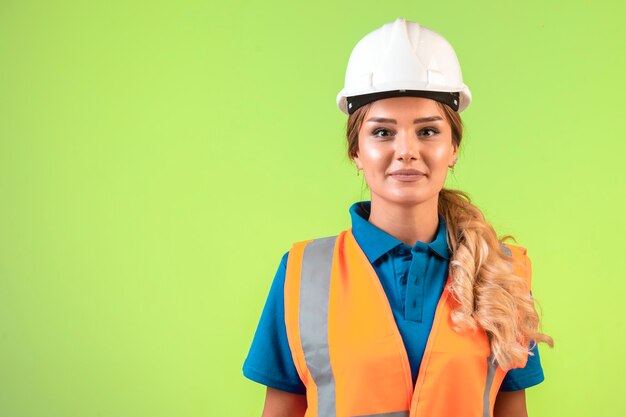 Vrouwelijke ingenieur die verantwoordelijk is in witte helm en uitrusting ziet er professioneel uit.