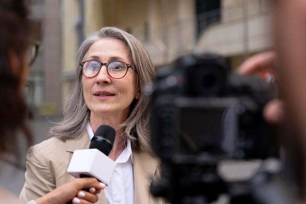 Gratis foto vrouwelijke journalist neemt een interview naast haar cameraman