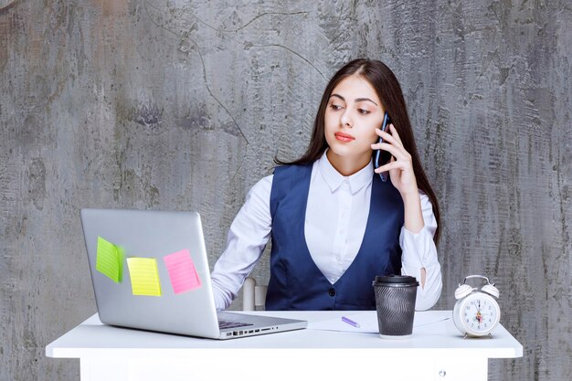 Vrouwelijke kantoormedewerker die werk bespreekt via mobiele telefoon. Hoge kwaliteit foto