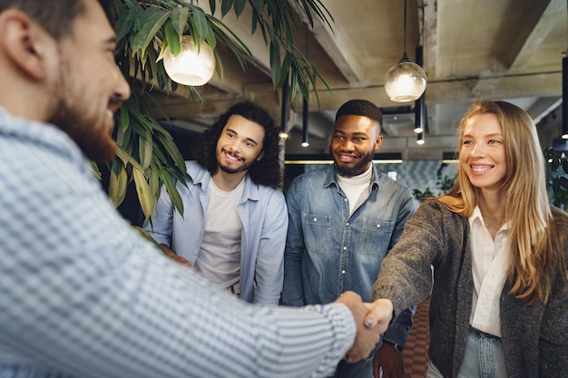 Gratis foto vrouwelijke kantoormedewerker schudt de hand van een nieuwe mannelijke medewerker van het teamlid