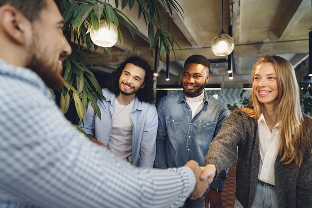 Vrouwelijke kantoormedewerker schudt de hand van een nieuwe mannelijke medewerker van het teamlid