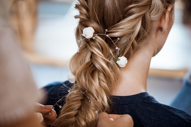 Vrouwelijke kapper die kapsel maakt aan blondevrouw in schoonheidssalon