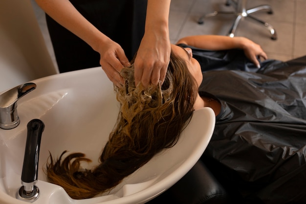 Gratis foto vrouwelijke klant die haar haar laat wassen bij de kapper