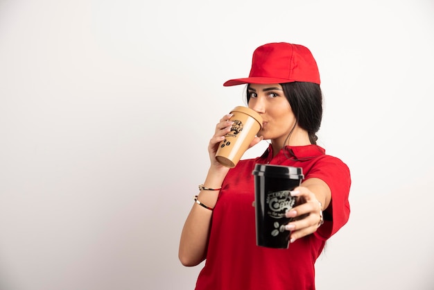 Vrouwelijke koerier die een kop van koffie op witte achtergrond drinkt. hoge kwaliteit foto