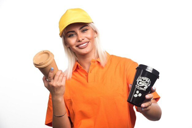 Vrouwelijke koerier die twee kopjes koffie op witte achtergrond houdt. Hoge kwaliteit foto