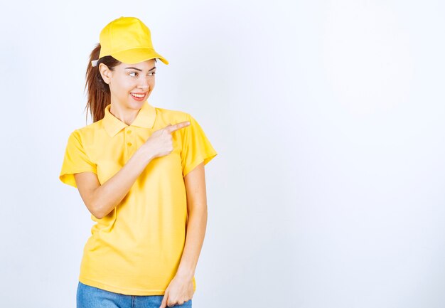 Vrouwelijke koerier in geel uniform wijzend naar ergens.