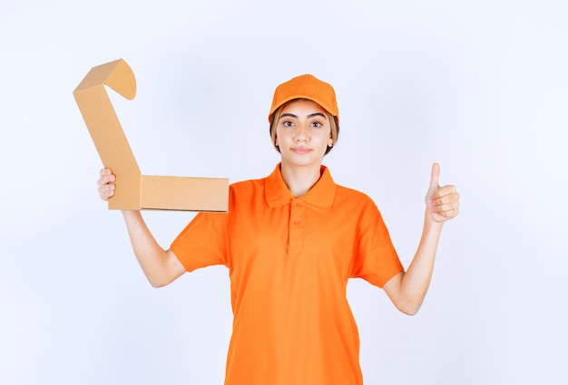 Vrouwelijke koerier in oranje uniform met een open kartonnen doos en een teken van plezier