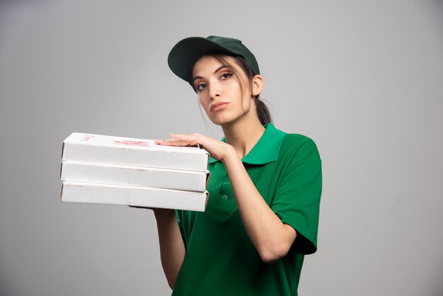 Vrouwelijke koerier poseren met pizzadozen