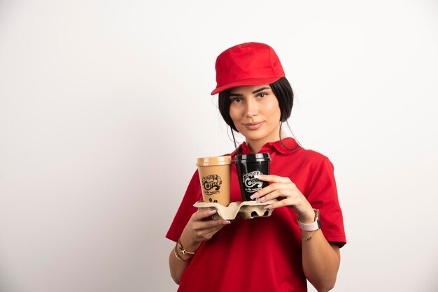 Vrouwelijke koerier poseren met twee kopjes koffie. hoge kwaliteit foto