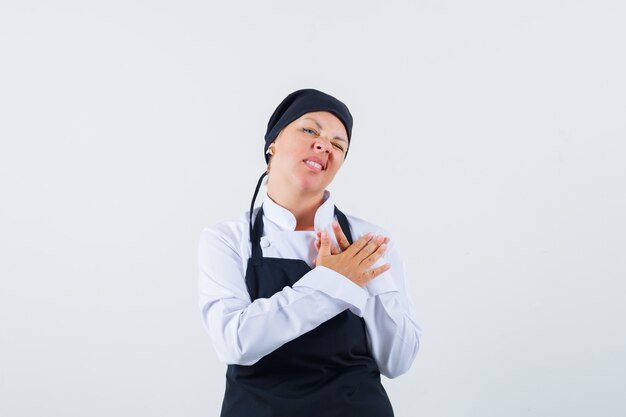 Vrouwelijke kok in uniform, schort hand in hand op de borst, vooraanzicht.