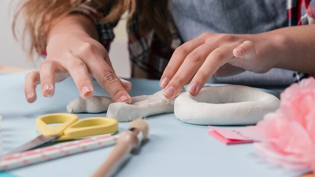 Vrouwelijke kunstenaar die brief met witte klei maakt