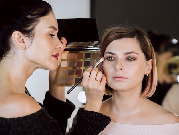 Vrouwelijke kunstenaar die make-up op model toepast