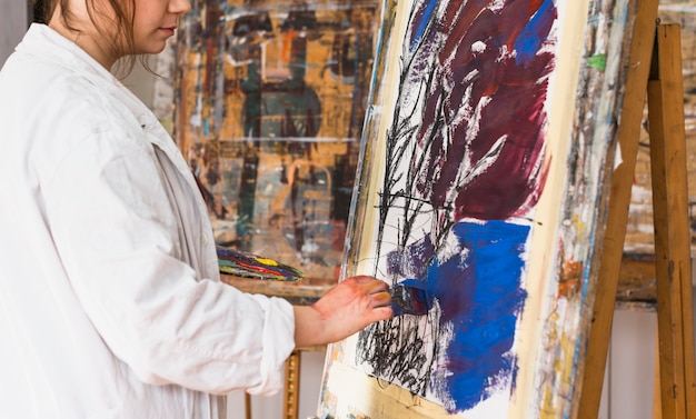 Vrouwelijke kunstenaar die met borstel op canvas op workshop schildert