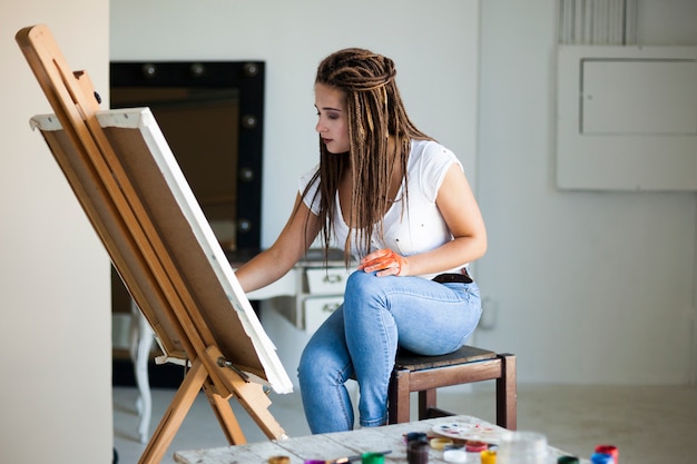Vrouwelijke kunstenaar die op canvas in studio schildert