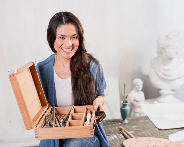 Vrouwelijke kunstenaar met houten doos van borstels