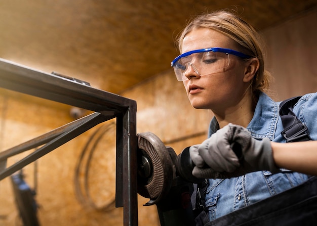 Gratis foto vrouwelijke lasser met behulp van haakse slijper