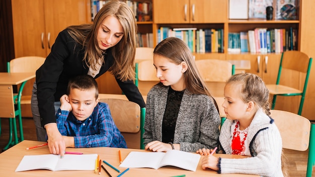 Vrouwelijke leraar die leerlingen helpt in het bestuderen van proces