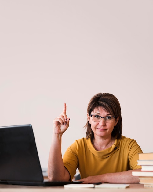 Gratis foto vrouwelijke leraar met laptop wijzen