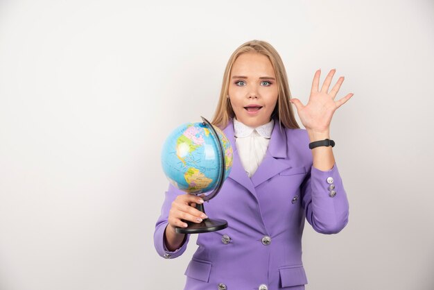 Vrouwelijke leraar poseren met globe op wit.