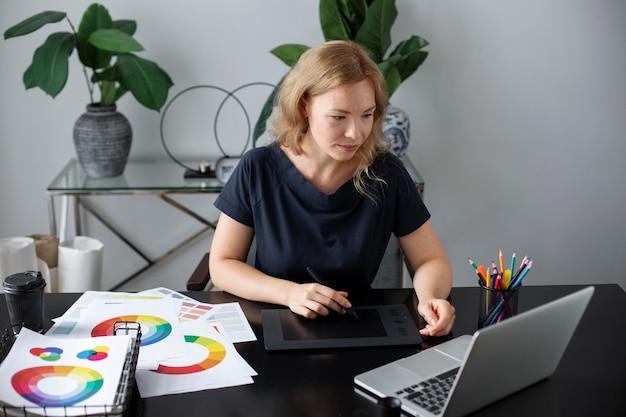 Vrouwelijke logo-ontwerper werkt op haar kantoor aan een grafisch tablet