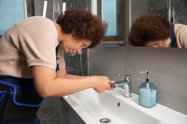 Gratis foto vrouwelijke loodgieter die problemen oplost in het huis van een klant