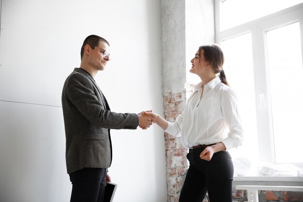 Vrouwelijke makelaar die nieuw huis toont aan een jonge mens na een bespreking over huisplannen, bewegend, nieuw huisconcept