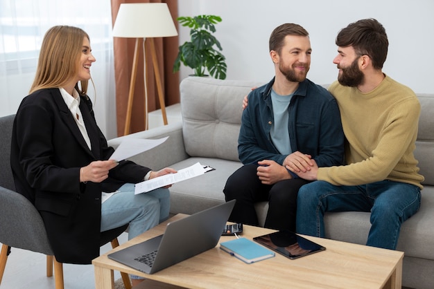 Gratis foto vrouwelijke makelaar in onroerend goed die over zaken praat en huis laat zien aan een homopaar