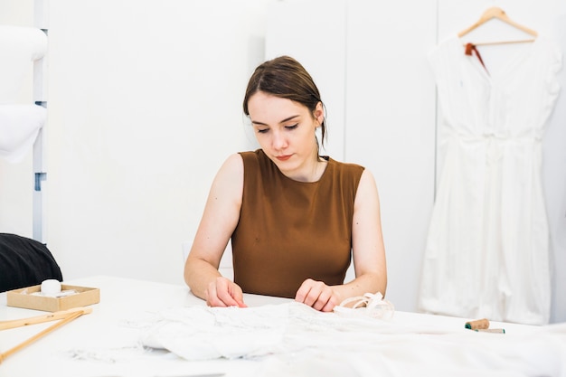 Gratis foto vrouwelijke manierontwerper die aan kleding in studio werkt