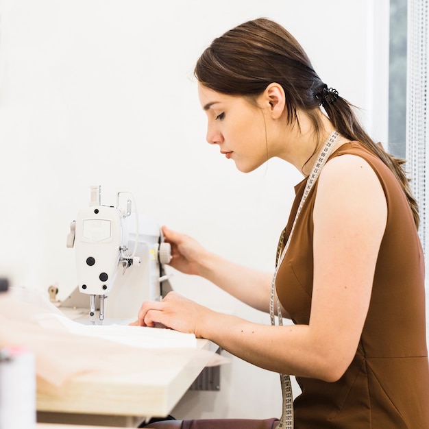 Gratis foto vrouwelijke naaister die aan naaimachine werkt