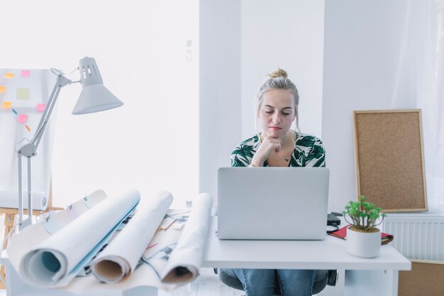 Vrouwelijke onderneemster die aan laptop op het werk werkt