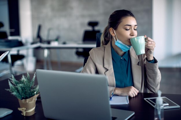 Vrouwelijke ondernemer genieten van een kopje verse koffie op kantoor