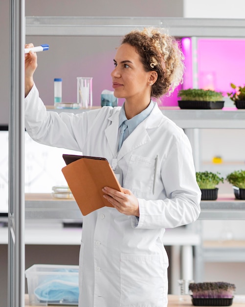 Gratis foto vrouwelijke onderzoeker in het biotechnologie laboratorium met tablet