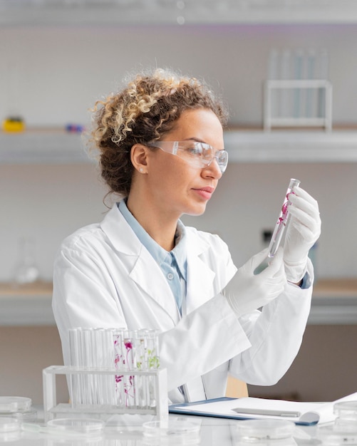 Vrouwelijke onderzoeker in het laboratorium met reageerbuizen en veiligheidsbril